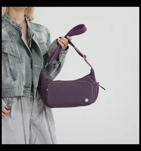 Dettaglio della borsa a tracolla in nylon viola indossata dalla modella, con tasca frontale.