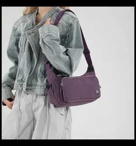Dettaglio borsa a tracolla in nylon viola, con tracolla regolabile e tasca anteriore.