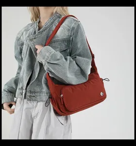 Dettaglio borsa a tracolla in nylon rosso, borsa casual con tasca frontale per uso quotidiano.