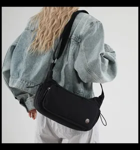 Vista dettagliata della borsa a tracolla in nylon nero, tasca anteriore e ampia cinghia.