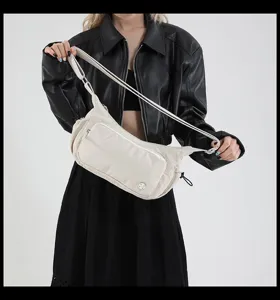 Dettaglio della borsa a tracolla in nylon beige, con tasca frontale e cinghia regolabile.
