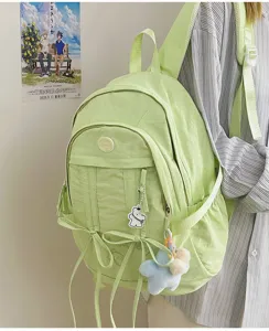 Light green nylon casual student backpack detail view, featuring cute charms and ribbons.