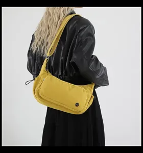 Vista dettagliata della borsa a tracolla gialla in nylon indossata dalla modella.