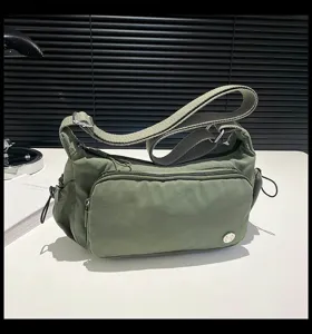 Dettaglio borsa a tracolla in nylon verde, tasche multiple, chiusura lampo, tracolla.