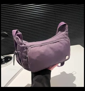 Dettaglio borsa a tracolla in nylon viola, design casual con tasche multiple con zip.