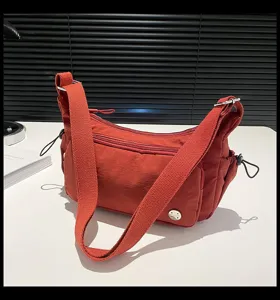 Borsa a tracolla in nylon rosso con cinghia larga e tasche multiple con zip per l'uso quotidiano.