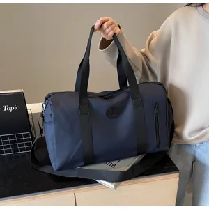 Vue détaillée du grand sac de voyage bleu foncé avec poignées robustes et bandoulière réglable.