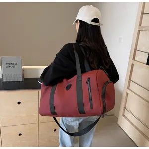 Vue détaillée d'un grand sac de voyage bordeaux avec des sangles noires et une poche zippée.