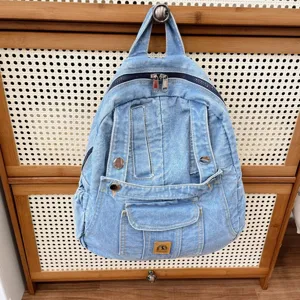 Detail view of casual light blue denim backpack hanging on wooden cabinet, retro style.