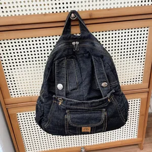 Detailed view of dark denim vintage style backpack with multiple pockets and metal hardware details