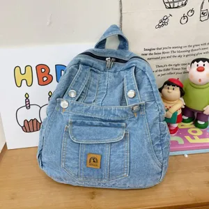 Vintage denim backpack detail showing classic blue wash fabric, metal rivets and front pocket.