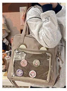 Cute beige ita bag with bear ears and clear PVC pocket for anime pins and daily student use.