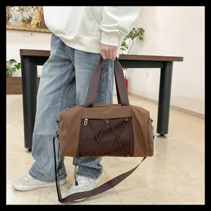 Detail view of brown gym duffel bag with mesh pocket and strap, ideal for travel and sports.