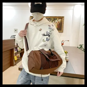 Detail view of brown gym duffel bag with mesh pocket and adjustable strap for sports travel.