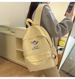 Close-up of cute puppy embroidered light yellow backpack with baseball pendant, casual style.