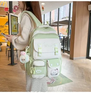 Detaillierte Seitenansicht eines frischen grünen Schulrucksacks mit Plüschanhänger im Café.