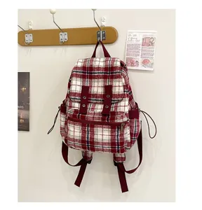 Detailed shot of vintage red white plaid backpack hanging on wall hook, cozy casual lifestyle.