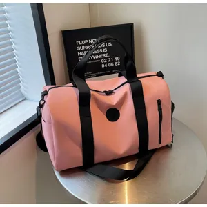 Vue détaillée d'un sac de voyage rose avec des sangle noires et des fermetures éclair robustes.