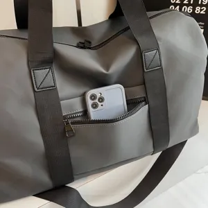 Gros plan détaillé du sac de voyage gris avec poche zippée avant et des sangles noires.