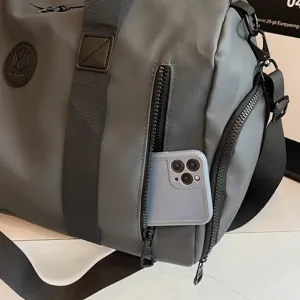 Détail de sac de voyage gris montrant le tissu en nylon résistant et la poche pour téléphone.