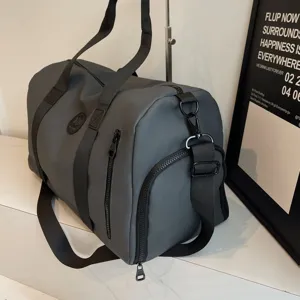 Grand sac de sport gris pour voyage imperméable avec bandoulière réglable et poches.