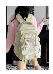 Niedlicher gelb-weißer Rucksack Detailblick mit süßem Plüsch Anhänger und praktischen Vordertaschen.