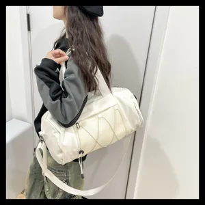 Detail view of a white gym duffel bag with mesh pocket and strap worn by model indoors.