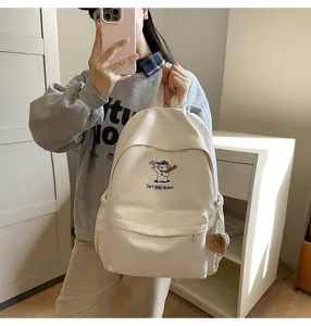 Detail view of the beige canvas backpack featuring cute baseball puppy embroidery.