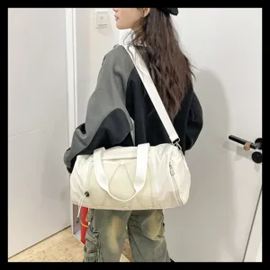 Detail view of white sports gym duffel bag with shoulder strap and mesh pocket in indoor scene.