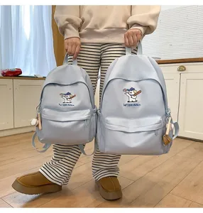 Detail shot showing large capacity light blue school backpack with cute embroidered puppy design.