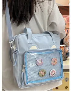 Light blue Ita bag with clear mesh pocket, cute bear ears and pin badges for anime fans.
