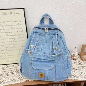 Vintage denim backpack detail showcasing light blue washed fabric, metal zippers and front pocket.