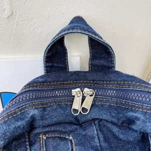 Denim backpack detail showing rugged fabric, dual metal zippers and vintage stitching.