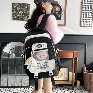 Großer schwarz-weißer Schulrucksack mit niedlichen Cartoon-Mustern und Plüsch-Anhänger.