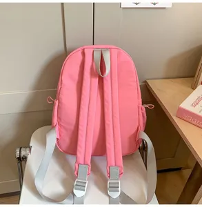 Detailansicht eines rosa Mini-Rucksacks mit grauen Schultergurten auf einem Stuhl im Zimmer.