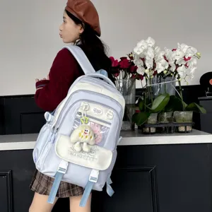 Detailansicht eines süßen hellblauen und weißen Studenten-Rucksacks mit Plüsch-Anhänger.