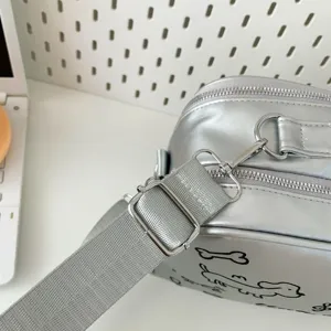 Silver crossbody ita bag detail shot with adjustable strap and cute cartoon dog print.