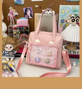 Pink ita bag detail view with transparent mesh window and cute bear ears for displaying pins.