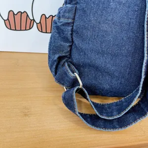 Detailed view of dark blue denim backpack strap and metal ring, casual vintage style.
