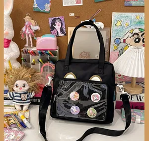 Detail shot of black canvas itabag with transparent front window, cute bear ears, and pin badges.