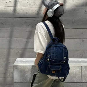 Detail view of the vintage denim backpack worn by model, showcasing multiple functional pockets.