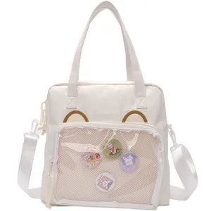 White canvas ita bag with transparent front pocket, cute bear ears and decorative pin badges.