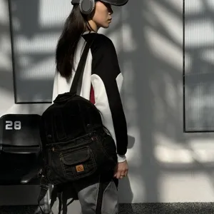 Detailed side view of a black denim backpack with workwear design and functional pockets.