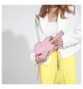 Unique pink guitar-shaped crossbody bag with glossy finish and chic trendy fashion style.