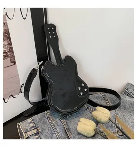 Close up view of the trendy black patent leather guitar shaped shoulder bag with metal studs.