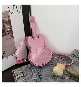 Close-up detail of the pink shiny guitar-shaped shoulder bag featuring rhinestone and heart accents.