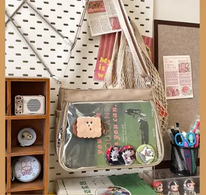 Close-up detail of the transparent front pocket ita bag, showing pins and decorative insert card.