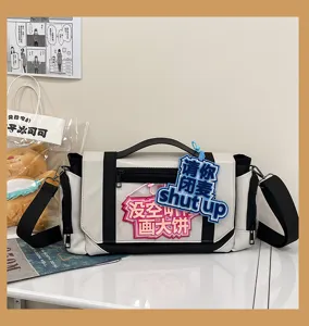 Close-up details of anime style black and white messenger it bag with badge window and straps.