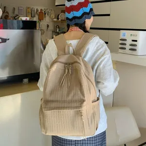 Vue détaillée du sac à dos beige décontracté porté, avec tissu plissé et poches de grande capacité.