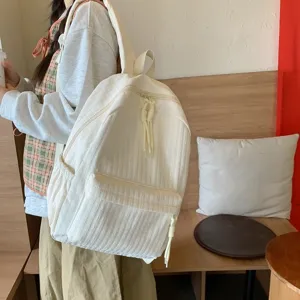 Gros plan détaillé du sac à dos crème décontracté montrant un tissu texturé et une poche avant.